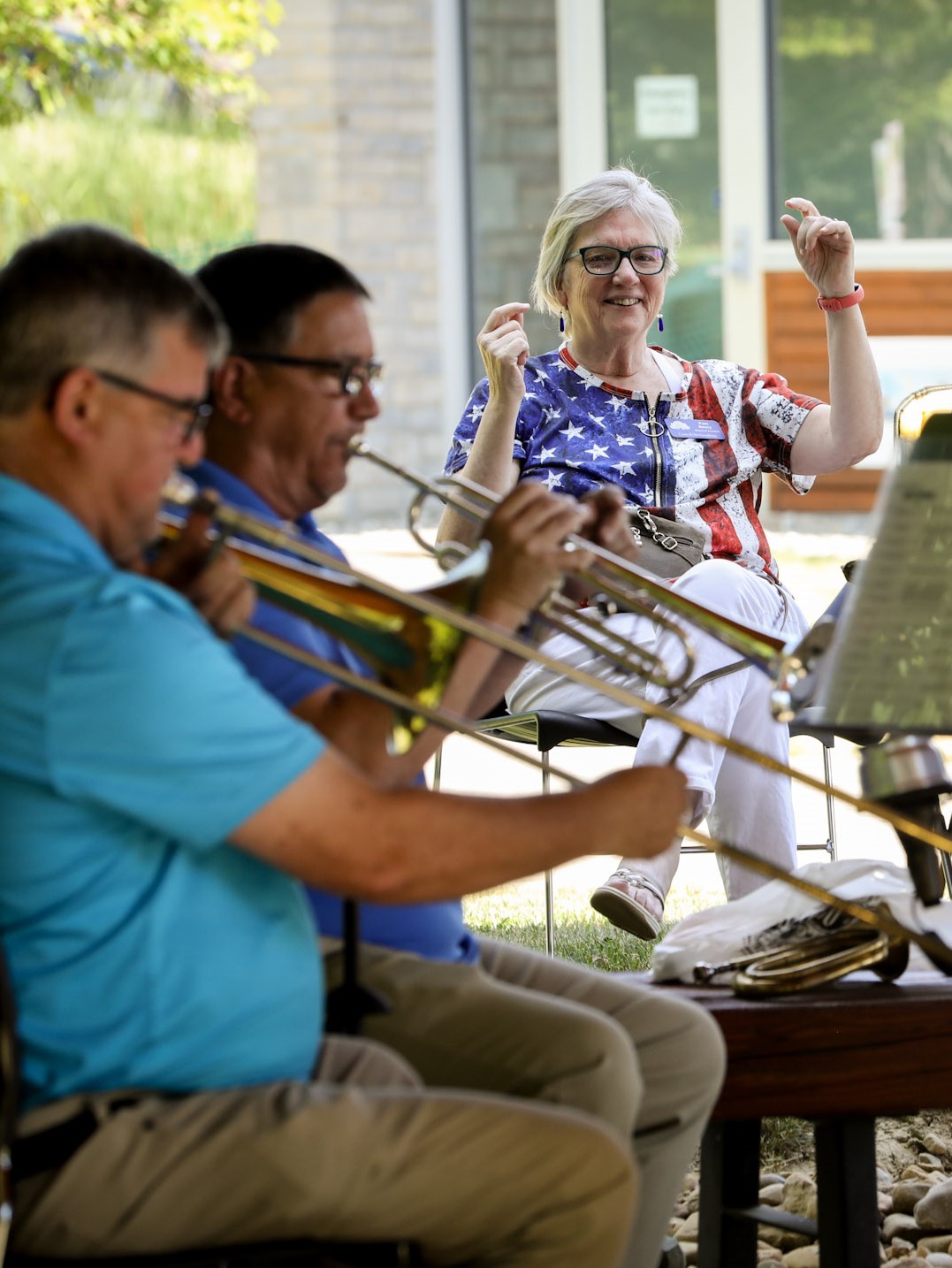A trombone and trumpet player perform while an audience member snaps their fingers to the music.