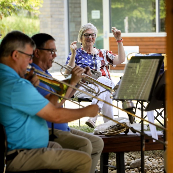 Central Ohio Symphony Brass Quintet. Two musicians play outside Orange Library while a woman waves her hands in enjoyment.